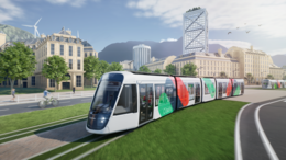 This artist's drawing shows a tram moving from right to left in an urban environment. The tram has a white livery with green, blue and red spots. It bears the Citadis name on its side and on the display above the windscreen. A second tram can be seen in the distance, on the right-hand side. The trams are travelling along a grassy avenue. Buildings can be seen in the background and mountains in the distance.